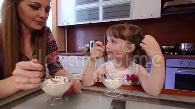 幸福的一家人在厨房里吃冰淇淋。可爱的小女孩在厨房的碗里吃冰淇淋。